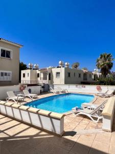 a swimming pool with lounge chairs and a house at Sirena Kings in Paphos