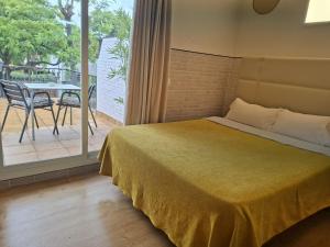 a bedroom with a bed and a balcony with a table at Hotel 139 in Castelldefels