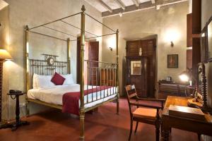 a bedroom with a canopy bed and a desk at Dune de L'orient in Pondicherry