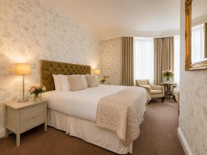 ein Hotelzimmer mit einem großen Bett und einem Stuhl in der Unterkunft Ashburn Hotel in London
