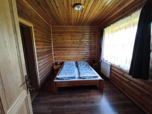 a small room with a bed in a wooden cabin at Vili Vendégház in Demjén