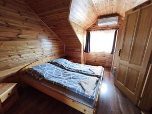 a bedroom with a bed in a wooden cabin at Vili Vendégház in Demjén