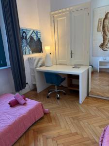 a bedroom with a desk and a bed with a pink blanket at Centro - doppia in casa d'artista in Turin