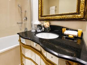 ein Badezimmer mit Waschbecken, Spiegel und Badewanne in der Unterkunft Ashburn Hotel in London