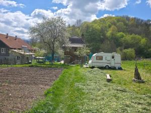 a white caravan parked in a yard next to a house at La Umbra Muntilor Traditional House in Ocoliş