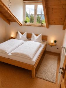 a large bed in a room with two windows at Helle Ferienwohnung im Bayerischen Wald mit Balkon, Garten & viel Platz für 4 in Mauth