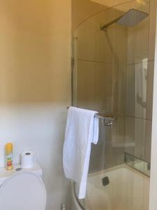 a bathroom with a shower and a toilet and a towel at Beautiful 2 bedroom unit, inverter & complex pool in Johannesburg +7 photos