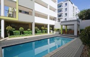 a swimming pool in front of a building at Beautiful 2 bedroom unit, inverter & complex pool in Johannesburg