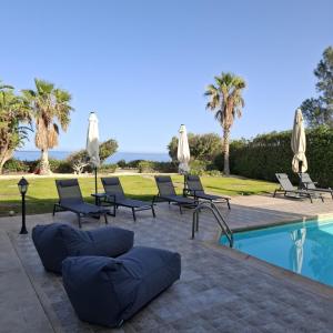 a group of chairs and umbrellas next to a pool at Olgas Villa in Ayia Marina