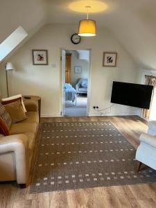 a living room with a couch and a flat screen tv at The Hayloft, Wonderful Riverside Accommodation in Bodenham