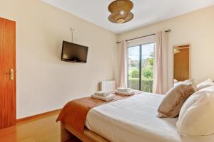 a bedroom with a bed with a tv and a window at Sweet Orchard Escape - By Wehost in Porto Moniz