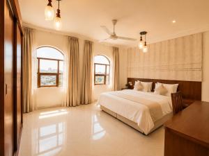 a bedroom with a bed and a desk and two windows at hotel Alsalam suites in Salalah