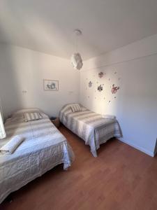 two beds in a room with white walls and wooden floors at La Serenité en Puerto Madryn in Puerto Madryn