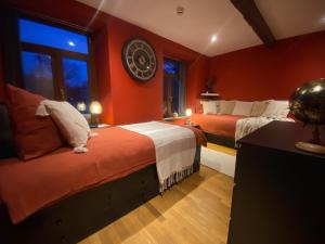 two beds in a room with red walls at La Forge - Chambres d'hôtes en Ardenne in Wellin