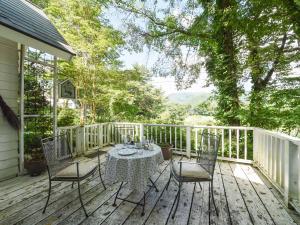 una terraza de madera con mesa y sillas. en Country Inn Orchard House, en Hokuto