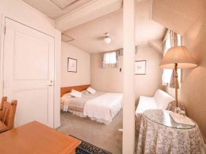 a bedroom with a bed and a table and a room with a bed at Country Inn Orchard House in Hokuto