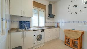 a kitchen with a washing machine and a clock on the wall at Monte la Torre in Santander
