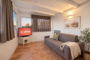 ein Wohnzimmer mit Sofa und Flachbildfernseher in der Unterkunft Lilly Rooms in Codaruina