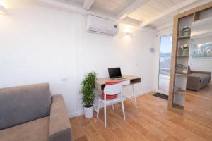 ein Wohnzimmer mit einem Schreibtisch, auf dem ein Laptop steht in der Unterkunft Lilly Rooms in Codaruina