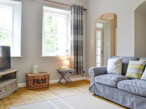 a living room with a couch and a television at The Old School House Cottage in Coupar Angus