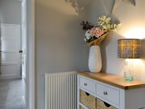 a room with a table with a lamp and flowers on it at The Old School House Cottage in Coupar Angus +10 photos