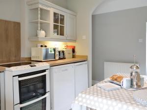 a kitchen with white cabinets and a counter top with a table at The Old School House Cottage in Coupar Angus
