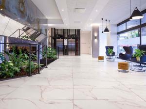 an office lobby with marble floors and plants at Mercure Biel in Biel