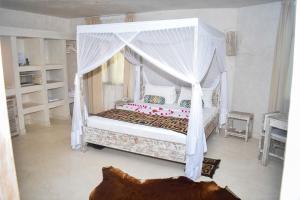 a bedroom with a bed with a canopy at The Villa Luxury Suites Hotel in Diani Beach