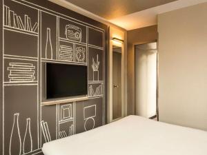a bedroom with a chalkboard wall with a television at ibis Bordeaux Centre Bastide in Bordeaux