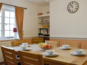 a dining room table with a bowl of fruit and a clock at Old Town Cottage in Sidmouth