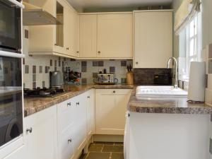 a kitchen with white cabinets and a sink at Old Town Cottage in Sidmouth
