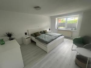a white bedroom with a bed and a window at Kastanienidyll in Grabowhöfe