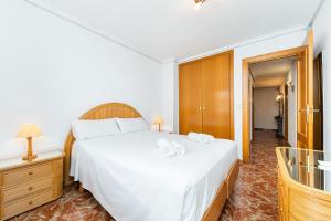 a bedroom with a large white bed with two towels at Sunrise Arts 2 in Torrevieja