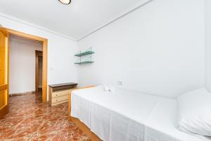 a white bedroom with a bed and a table at Sunrise Arts 2 in Torrevieja