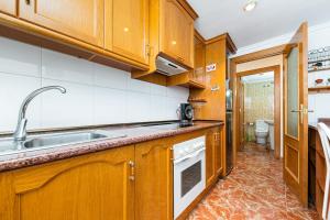 a kitchen with wooden cabinets and a sink and a toilet at Sunrise Arts 2 in Torrevieja