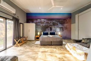 a bedroom with a bed and a painting on the wall at Wild Villas in Victoria Falls +35 photos