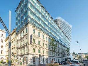 a tall building on a city street with a car at Novotel Wien City in Vienna