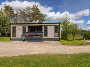 a small house with a porch on a field at Dobby Lodge in Bassenthwaite