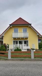 a yellow house with a white balcony on top at 'Seeperle' am Strand des Kummerower Sees in Verchen