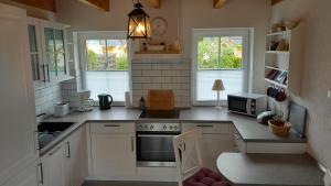 a kitchen with white cabinets and a stove top oven at 'Seeperle' am Strand des Kummerower Sees in Verchen