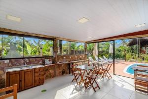 an open kitchen with tables and chairs and a pool at Beautiful Pousada in the middle of nature in Bombinhas in Canto Grande