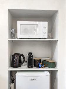 a microwave oven sitting on a shelf above a refrigerator at Arpi Uno in Foggia