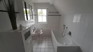 a white bathroom with a tub and a sink at 'Seeperle' am Strand des Kummerower Sees in Verchen +12 photos