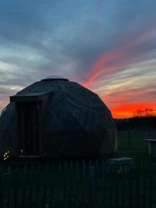 a large dome building with a sunset in the background at Dôme géodésique in Brie