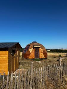 a yurt in a field next to a fence at Dôme géodésique in Brie
