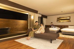 a woman and child sitting on a couch in a hotel room at Ooedo Onsen Monogatari Premium Enakyo in Ena