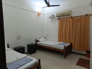 a room with two beds and a ceiling fan at Panchavadi Beach Resort in Varkala