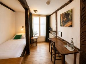 a room with a bed and a desk and a table at Hotel Pemü in Arnsberg