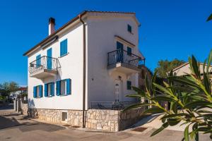 a white building with blue shutters on a street at Apartments Celebrini in Malinska