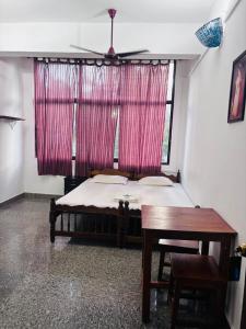 a bedroom with a bed and a window with pink curtains at Panchavadi Beach Resort in Varkala